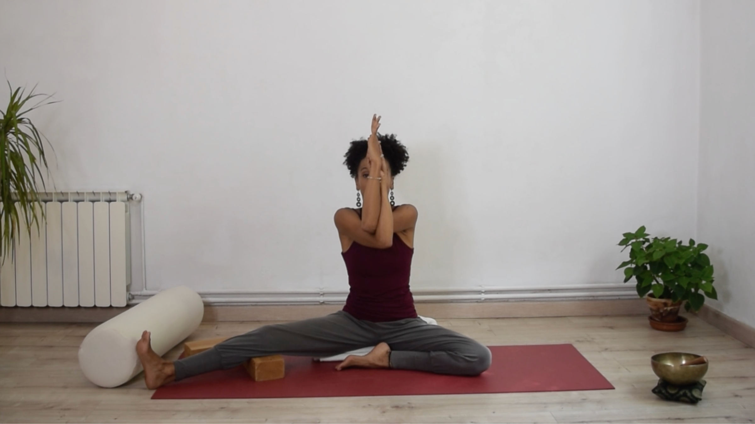 A practitioner sitting in Half Butterfly with arms crossed at the elbows and forearms wrapped together in front of the chest.